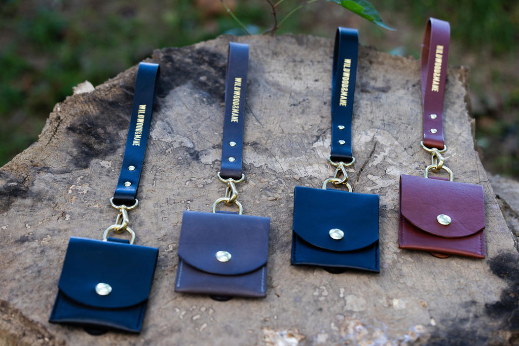 Set of four wallets with wrist straps on a tree stump with blurred natural background