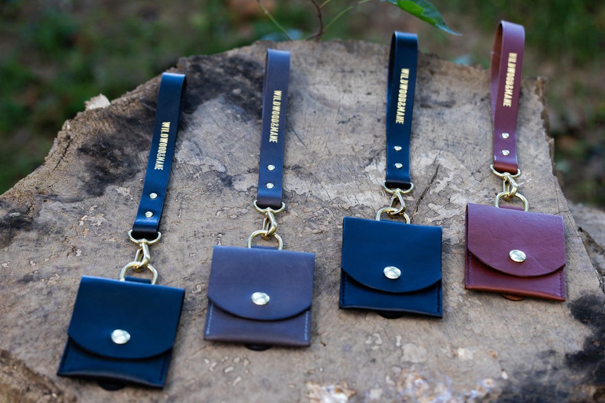 Set of four wallets with wrist straps on a tree stump with blurred natural background